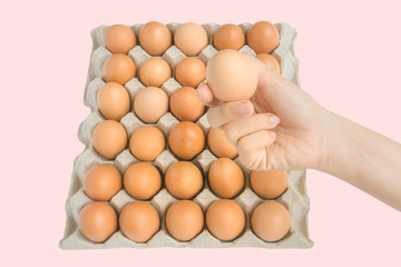 Close-up young woman hand hold a fresh and raw brown chicken egg, egg box as beautiful background. Organic eggs.Natural healthy food and organic farming concept. Clipping path and copy space.