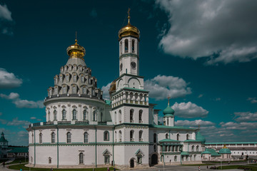 Fototapeta na wymiar Orthodox New Jerusalem Monastery made of white stone with golden domes and turquoise rooftops against a blue sky. Famous Landmark near Moscow