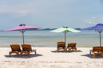 Lounge chairs and colorful umbrella at the white sand beach