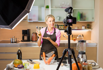 Woman recording video in her home kitchen, creating content for video blog