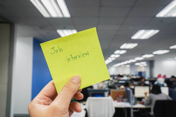 people holds postit with job interview reminder in office