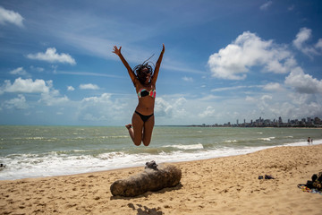 Black woman jumping on the beach.