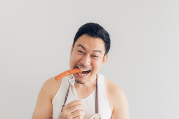 Happy man is eating the delicious favorite sausage he cooked himself.