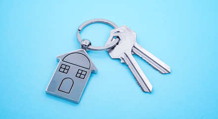 key chain with house symbol and keys on blue background,Real estate concept