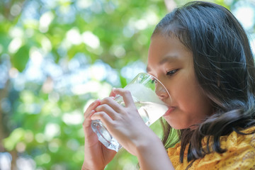 Obraz premium The girl is drinking cold water from the glass.