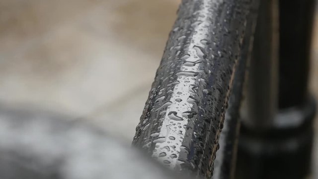 A handheld shot focusing on the water on this black pole from the rain