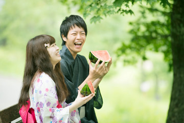 スイカを持ち微笑む浴衣姿のカップル