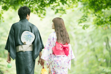 浴衣姿で手をつなぐカップルの後姿