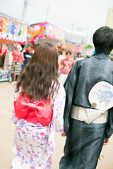 お祭りで手をつなぐカップルの後姿