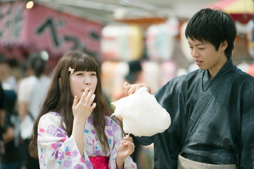 お祭りでわたあめを食べるカップル