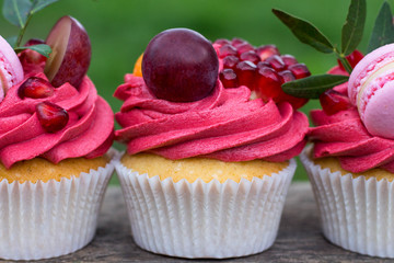 appetizing cupcakes decorated with macarons grape and pomegranate
