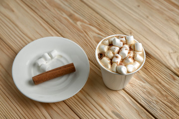 Hot morning coffee with marshmallow and cinnamon on a wooden sta