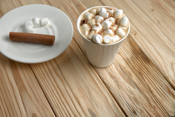 Hot morning coffee with marshmallow and cinnamon on a wooden sta