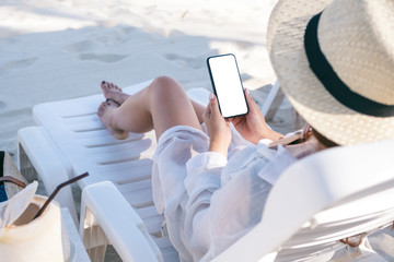 Mockup image of a woman holding black mobile phone with blank desktop screen while laying down on...