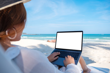 Mockup image of a woman using and typing on laptop computer with blank desktop screen while laying...