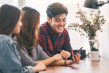 Three young asian people using and looking at the same mobile phone together