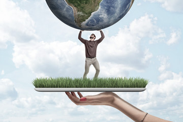 Female hand with small man in casual clothes holding earth globe on green grass model with blue sky background