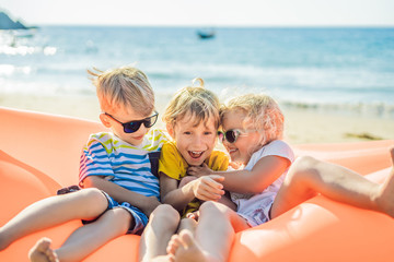 Children sit on an inflatable sofa against the sea and have fun