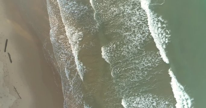 Drone spiriling up over the sea above the waves rolling in at Mae Pim beach Rayong Thailand