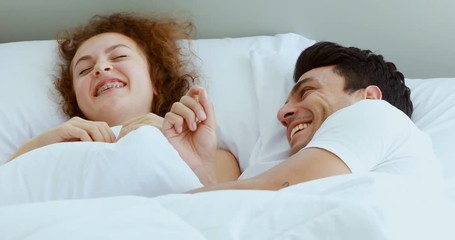 Close up scene video of Caucasian couple lie down on bed in bedroom, they talking and laughing together. - Powered by Adobe