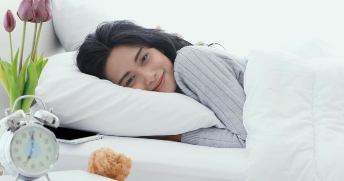 Close up scene video of beautiful Asian woman lie down on bed in bedroom, then she open her eyes and smile.