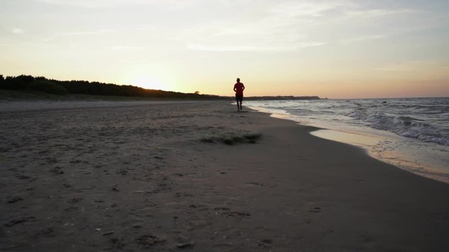 man running on the beach at the baltic sea during sunset in Swinoujscie, Poland