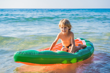 The boy swims in the sea on an inflatable mattress