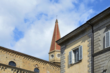 Fototapeta na wymiar urban view of Arezzo historic center with an ancient building facade and the Cathedral in the background, under the cloudy and sunny sky