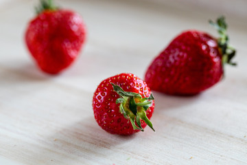Sweet, ripe, fresh strawberry of brightly red color in a wattled basket on a wooden table. Ready photo background. Soft focus. Macro.