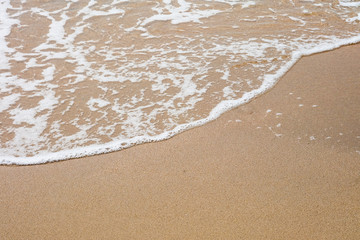 Fototapeta na wymiar The sea and the white wave ripples on the empty sand beach