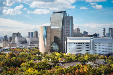 Fototapeta premium Widok z zamku w Osace z jesiennym parkiem zamkowym na pierwszym planie i panoramą miasta i Muzeum Historii Osaki w Japonii w tle.