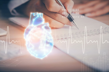 Heart hologram over woman's hands writing background. Concept of Medical education study. Double exposure