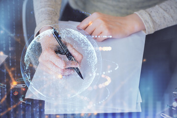 Multi exposure of hands making notes with world map hologram and data theme icons. Concept of global computer data.
