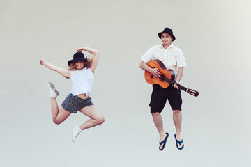 Fototapeta na wymiar Man with guitar and woman jumping