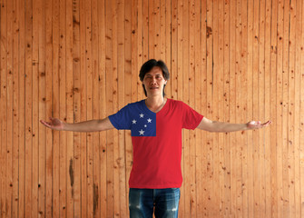 Man wearing Samoa flag color shirt and standing with arms wide open on the wooden wall background.