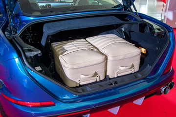 Cream big luggages inside the trunk of blue car