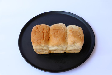 Loaf bread in the black round plate on the white base.