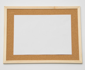 Blank white piece of letter sized paper on a cork notice board.