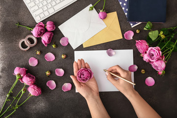 Woman writing something on table with beautiful pink flowers