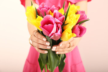 Young woman with bouquet of beautiful tulip flowers on light background, closeup