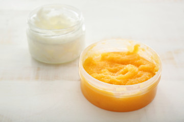 Jar with orange body scrub on light table