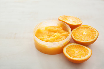 Fototapeta na wymiar Jar with orange body scrub on light table