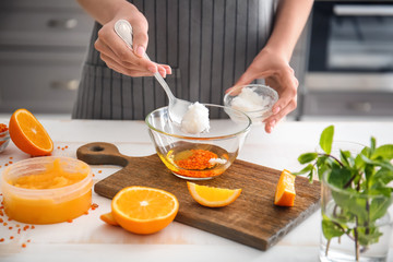 Woman preparing body scrub at table in kitchen