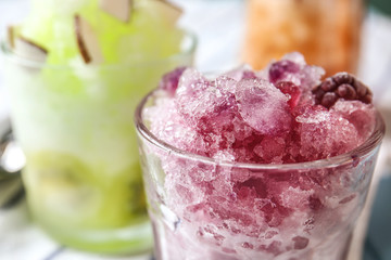 Glass with tasty shaved ice on table, closeup