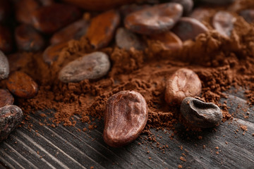 Cocoa beans and powder on wooden background, closeup