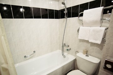 Bathroom in the apartment with white marble tiles with bath, toilet and wash basin