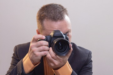Fototapeta premium Young male video cameraman, photographer, shoots video or takes a photo on the camera.