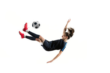 Fototapeta premium Young female football or soccer player with long hair in sportwear and boots kicking ball for the goal in jump isolated on white background. Concept of healthy lifestyle, professional sport, hobby.