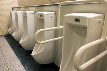 A line of urinals at a public toilet. Pure men's toilets in a department store. Public toilets for...