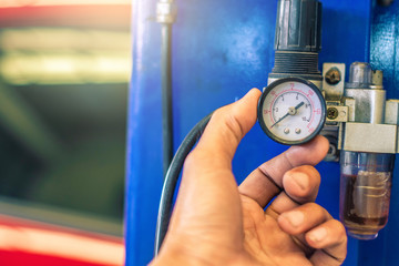 Man holding manometer with valve in car industry and car service on blurred background.